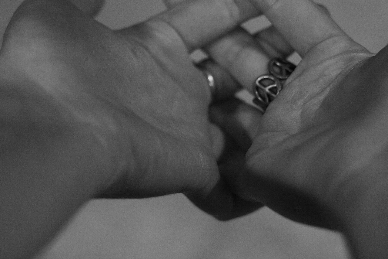Des mains rapprochées portant une bague avec un symbole de paix